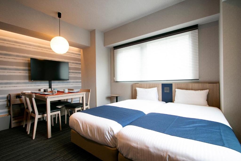 um quarto de hotel com uma cama e uma secretária com um computador em Minn Nishi-Kasai em Tóquio