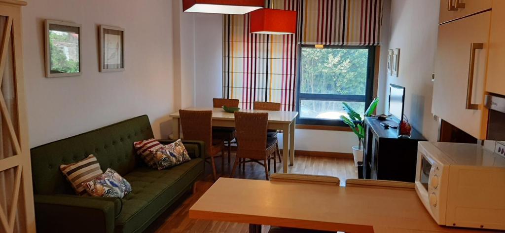 ein Wohnzimmer mit einem grünen Sofa und einem Tisch in der Unterkunft APARTAMENTO CENTRO DE SANXENXO con GARAJE in Sanxenxo