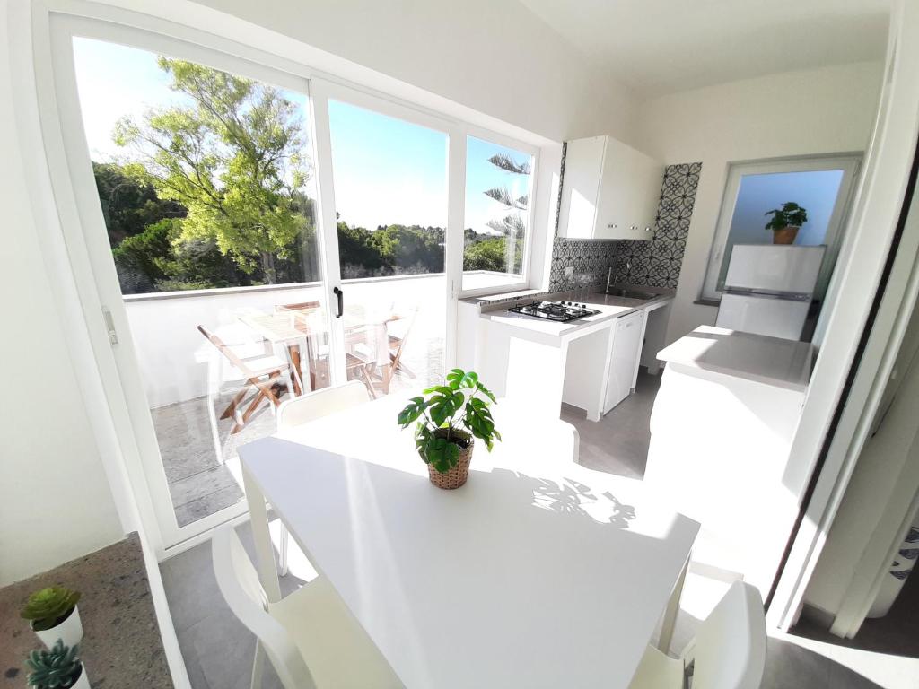una cucina e una sala da pranzo con tavolo e sedie bianchi di Otranto Casetta del Turchese a Otranto