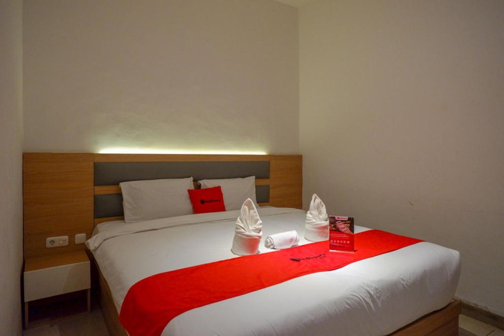 a bedroom with a large bed with a red blanket at RedDoorz Plus @ Losari Makassar in Makassar
