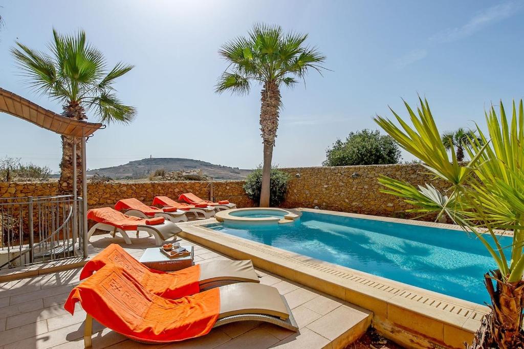 uma piscina com espreguiçadeiras e uma piscina em Tfiefa Holiday Home em Xagħra