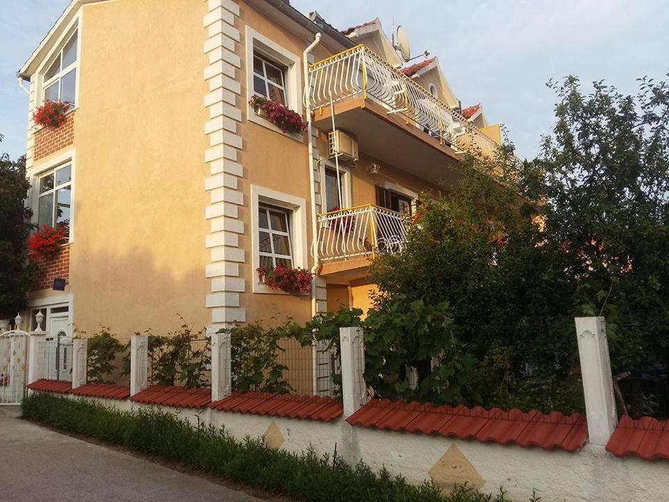 a yellow building with balconies and flowers on it at Apartmani Katarina in Brodarica