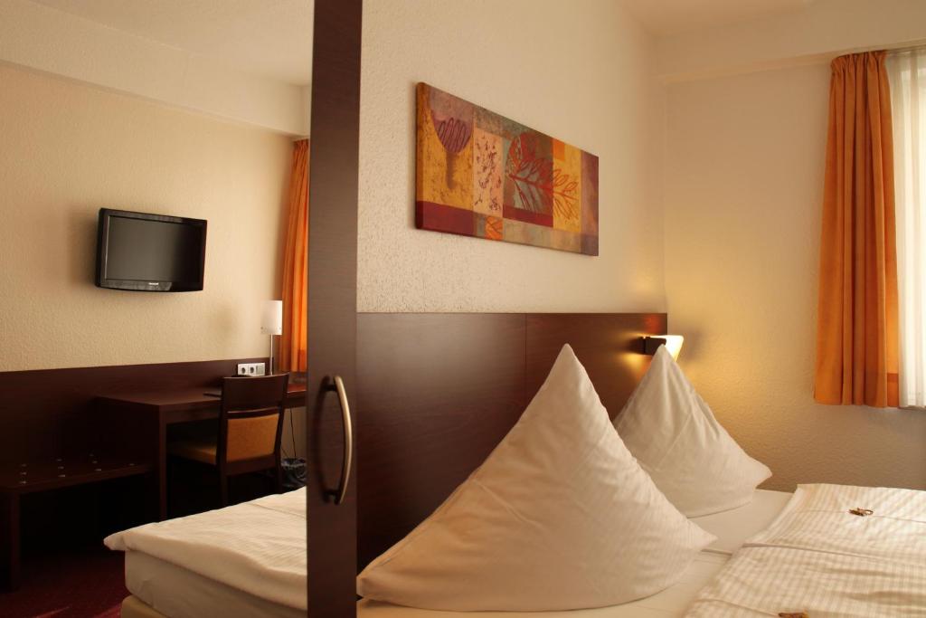 ハノーファーにあるハウス シュパークール ホテル ガルニのベッド2台とテレビが備わるホテルルームです。