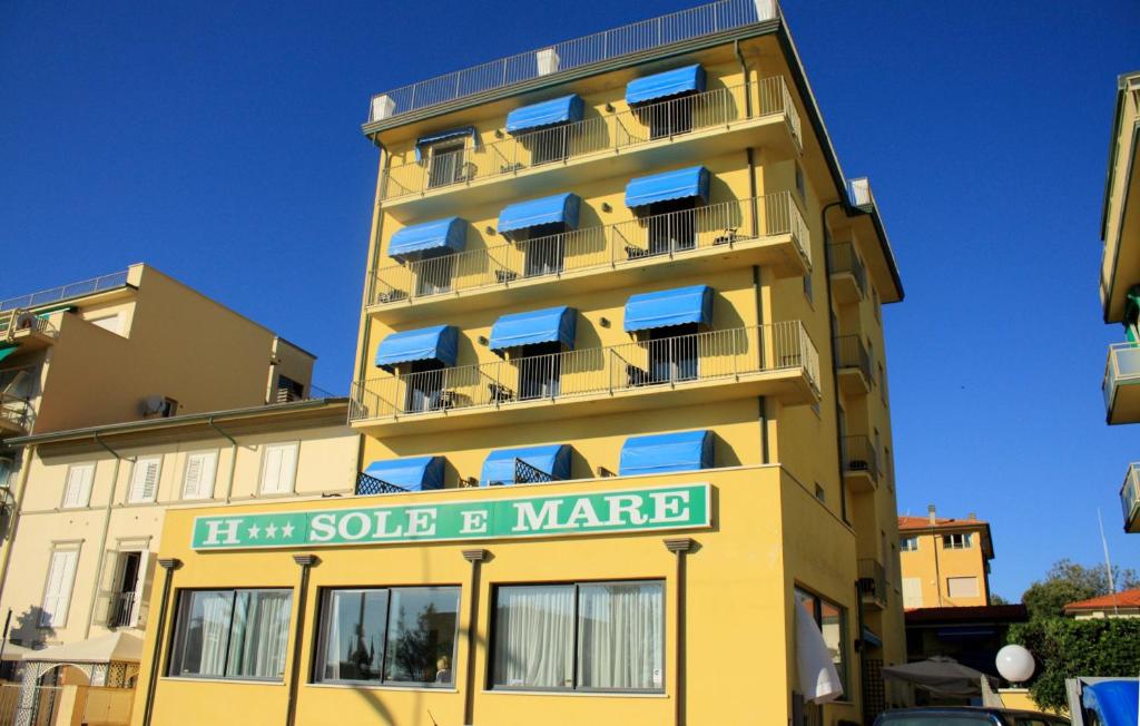 żółty budynek z niebieskimi balkonami i znakiem na nim w obiekcie Hotel Sole E Mare w mieście Lido di Camaiore