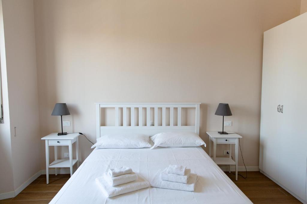 een slaapkamer met een wit bed en 2 witte tafels bij Comfy Apartment Near Fortezza Da Basso in Florence