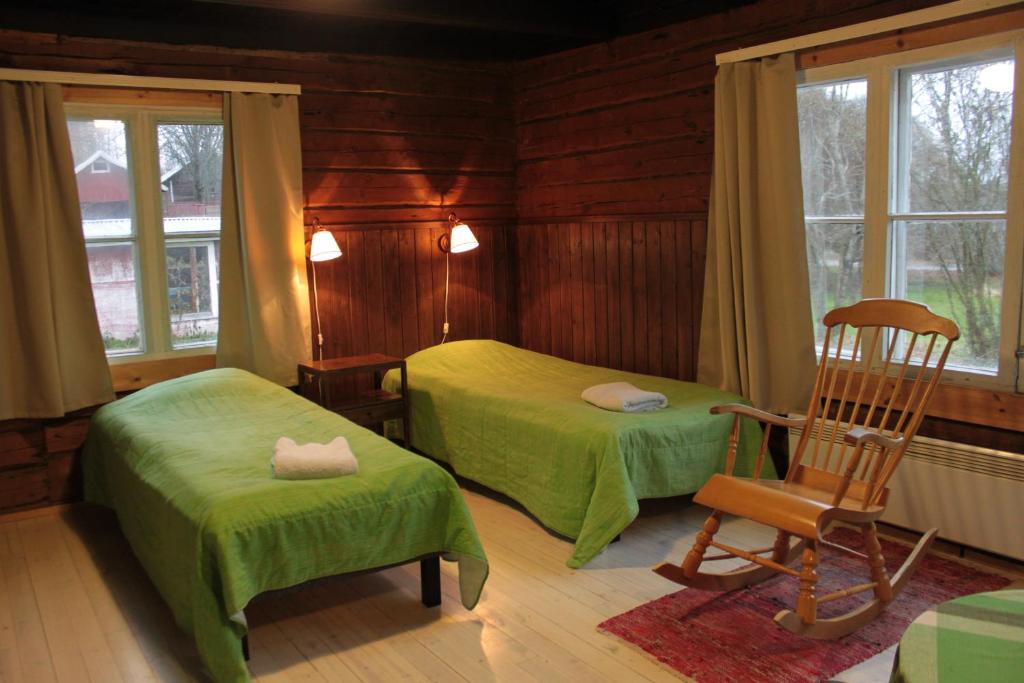 1 dormitorio con 2 camas y mecedora en Löydön Kartano, en Ristiina