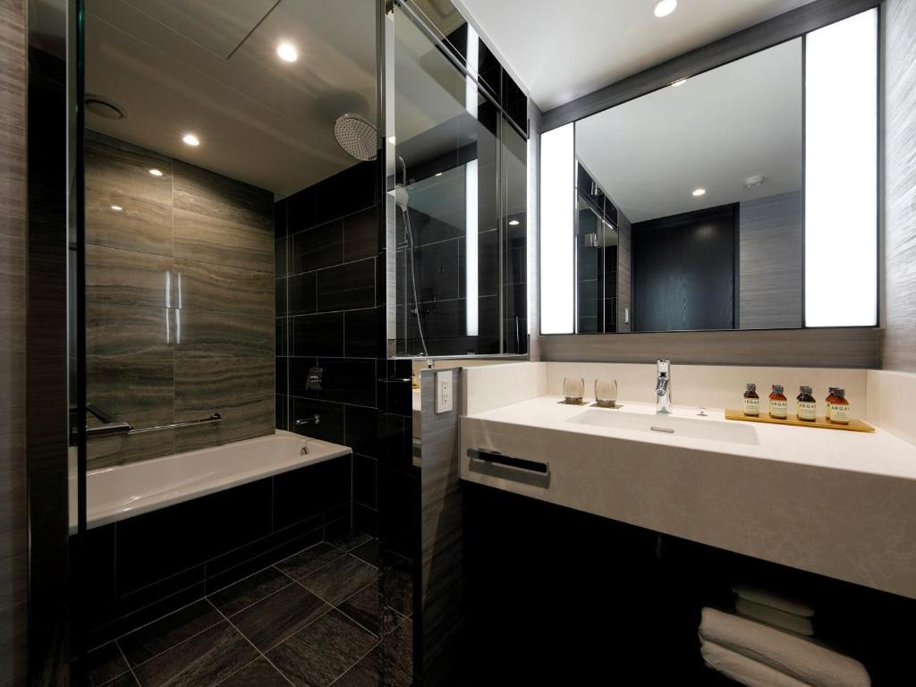 a bathroom with a sink and a tub and a shower at THE HOTEL SANRAKU KANAZAWA 21th December 2022 OPEN in Kanazawa