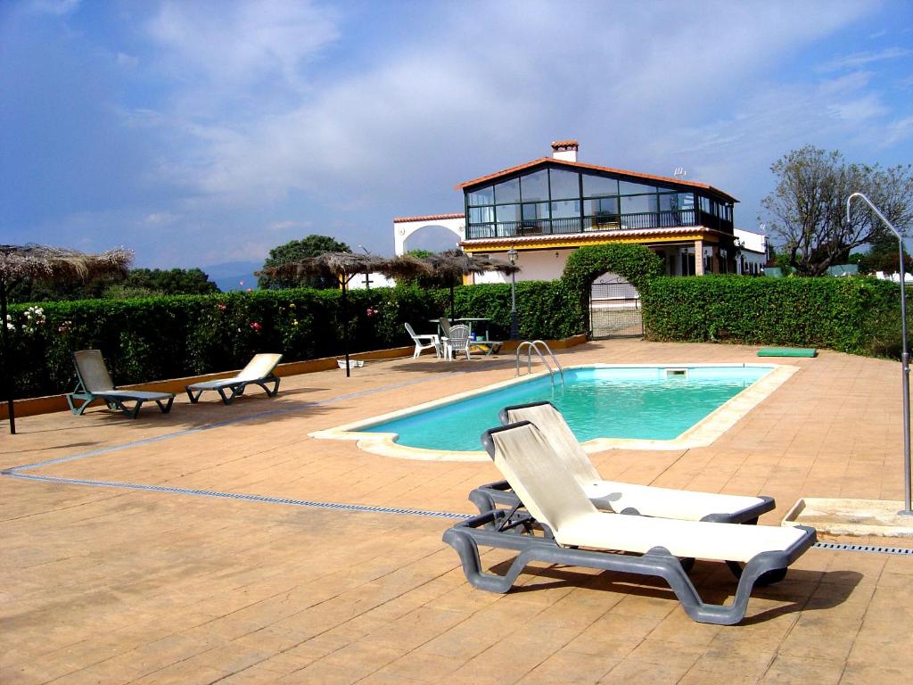 una piscina con 2 tumbonas y una casa en Casa Rural La Sierra de Monfragüe, en Malpartida de Plasencia
