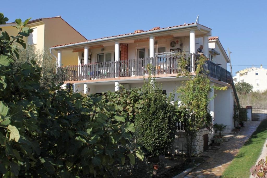 a white house with a balcony and bushes at Apartments with a parking space Liznjan, Medulin - 7224 in Ližnjan