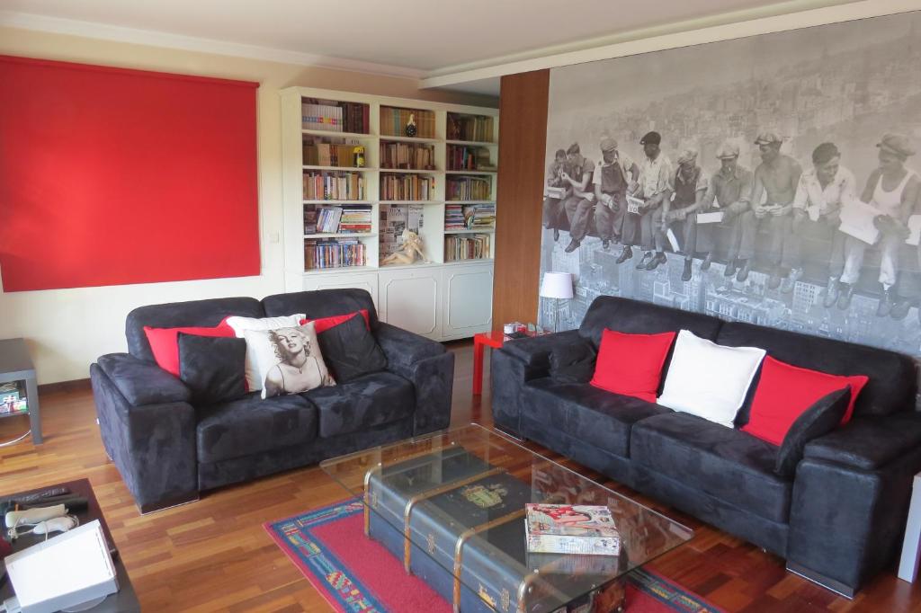 uma sala de estar com dois sofás pretos e uma parede vermelha em Sweet Home Braga Hostel & Guest House em Braga