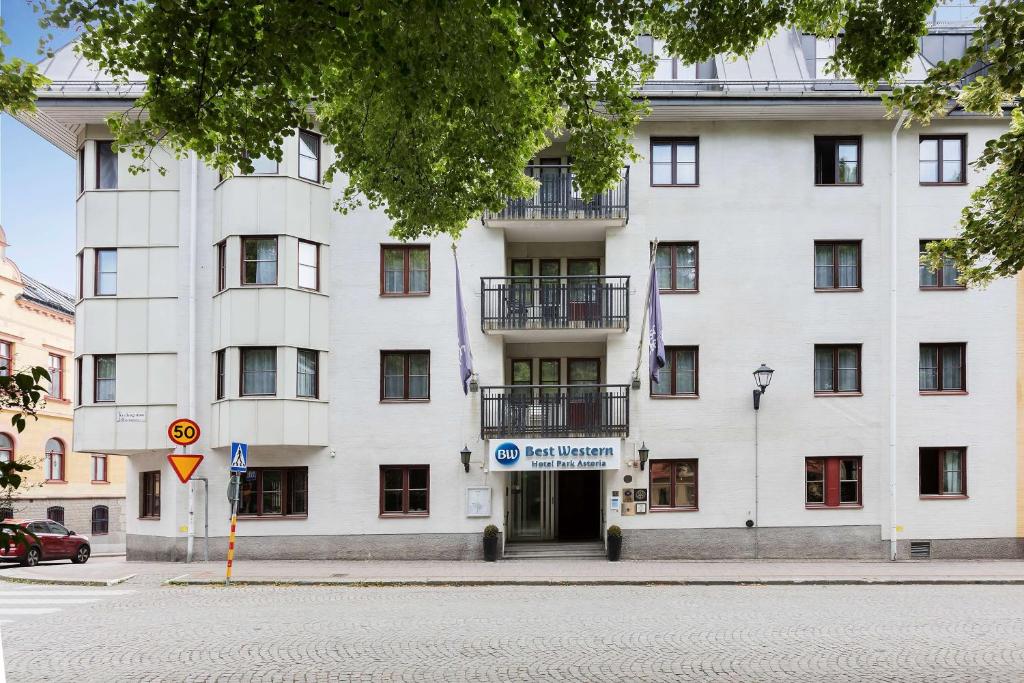 ein weißes Gebäude mit einem Schild davor in der Unterkunft Best Western Hotel Park Astoria in Enköping