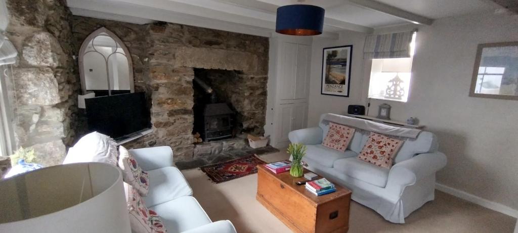 a living room with a couch and a fireplace at Samphire Cottage in Helston