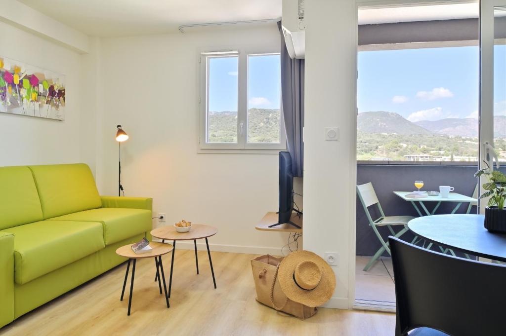 ein Wohnzimmer mit einem grünen Sofa und einem Tisch in der Unterkunft Résidence Easy Lodge in Ajaccio