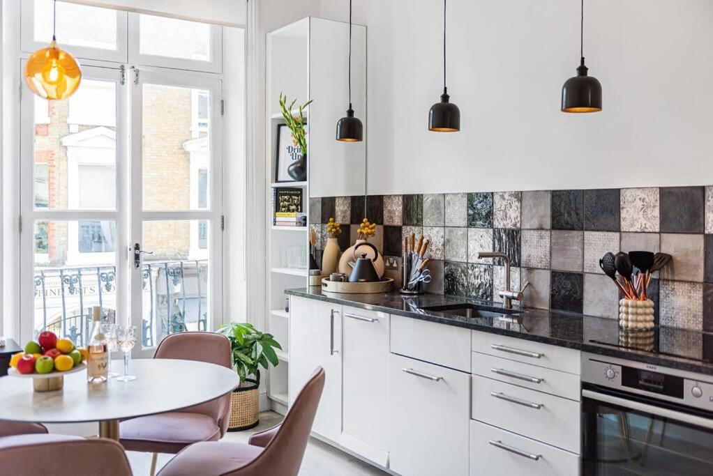 a kitchen with white cabinets and a table and chairs at Lady on the Lane- 2 bed Primrose Hill in London