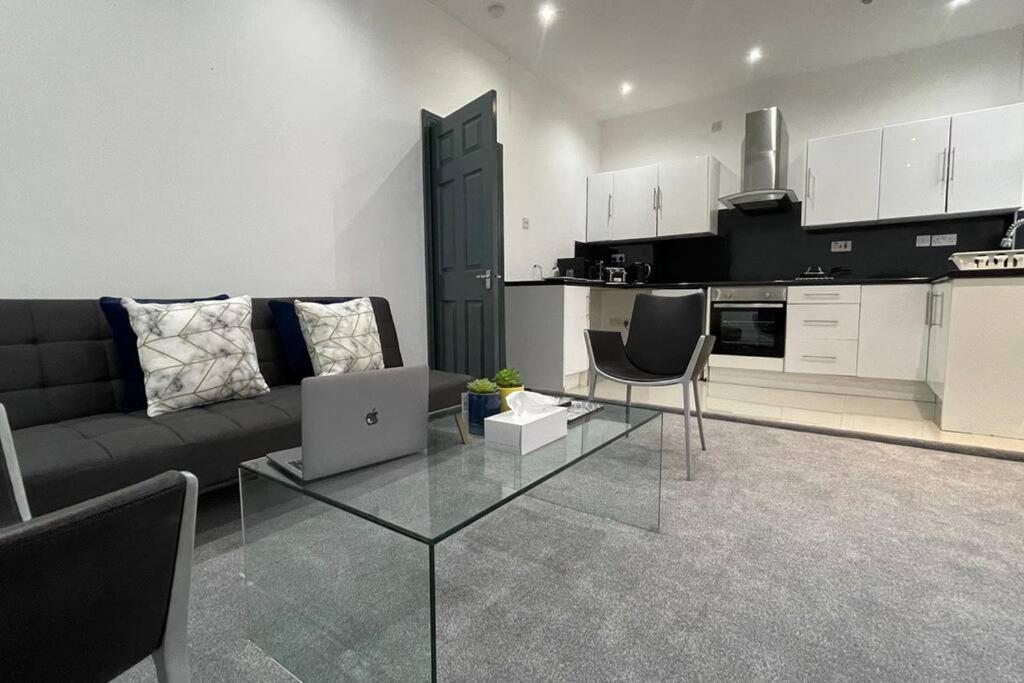 a living room with a couch and a kitchen at Suite 1- Luxury 1 Bed Apt- Leicester City- Free Parking in Leicester