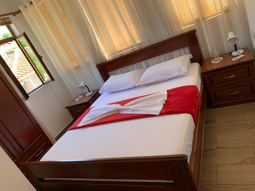 een slaapkamer met een bed met witte en rode lakens bij B&BSheshalliu in Berat