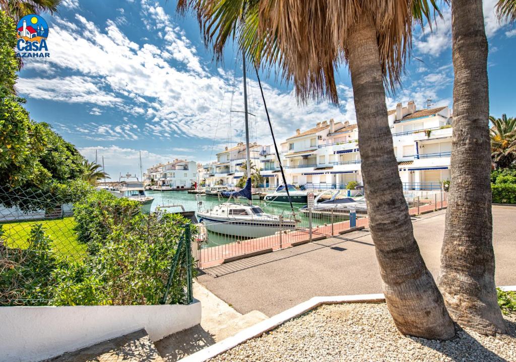 una palmera junto a un puerto deportivo con barcos en Apartamentos Poblado Marinero Casa Azahar, en Alcossebre
