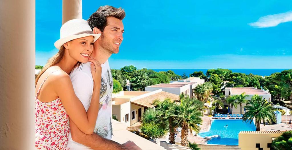 een man en een vrouw op een balkon met uitzicht op een resort bij Villaggio Cala Mancina in San Vito lo Capo