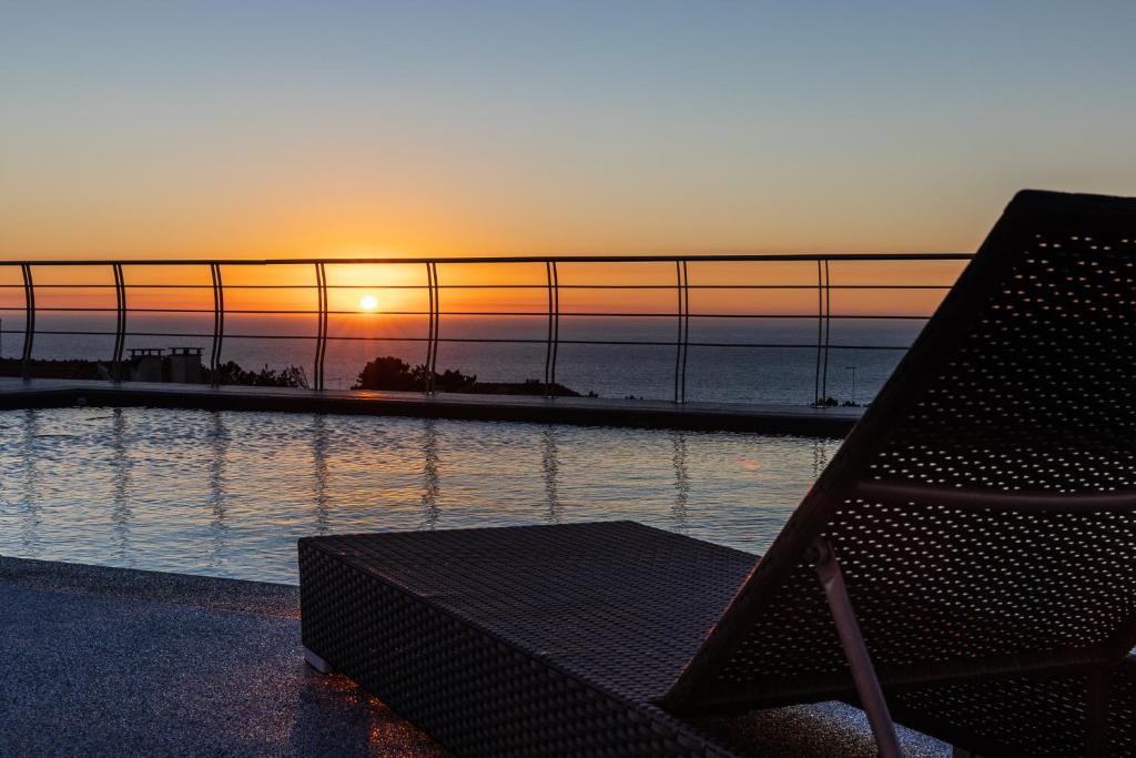 um banco em frente a uma piscina com o pôr-do-sol em Océane Bed and Breakfast na Nazaré