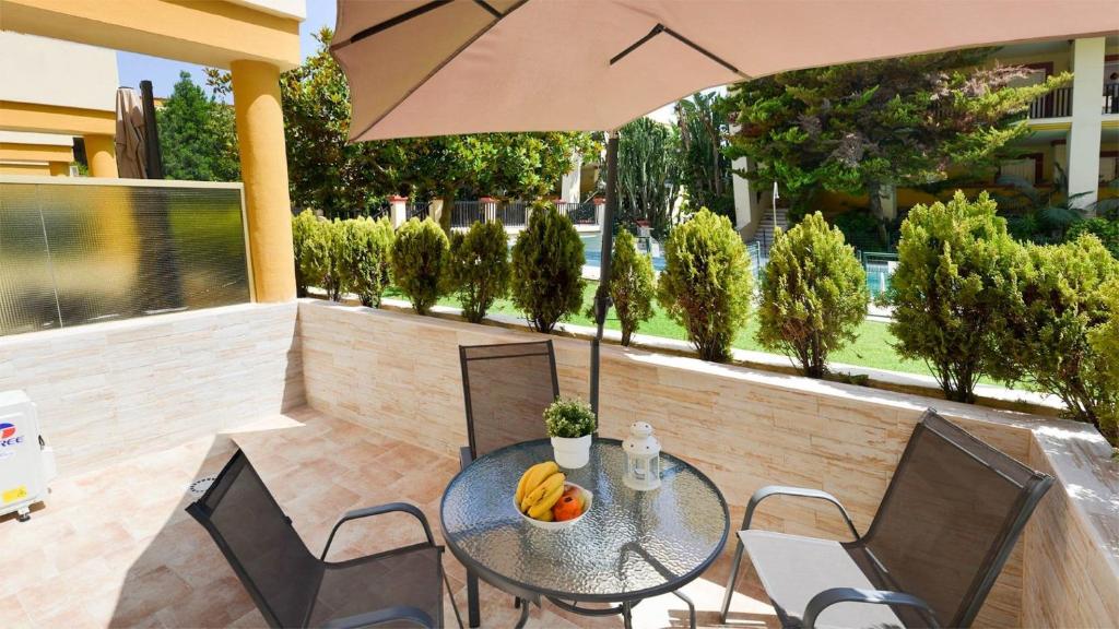 uma mesa e cadeiras com um guarda-sol num pátio em Apartamentos Romana Playa 203 em Marbella