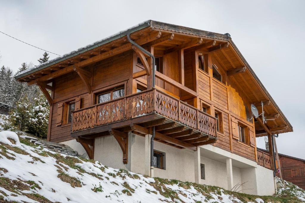 a wooden house with a balcony on top of a hill at Chalet Hibou in Les Gets