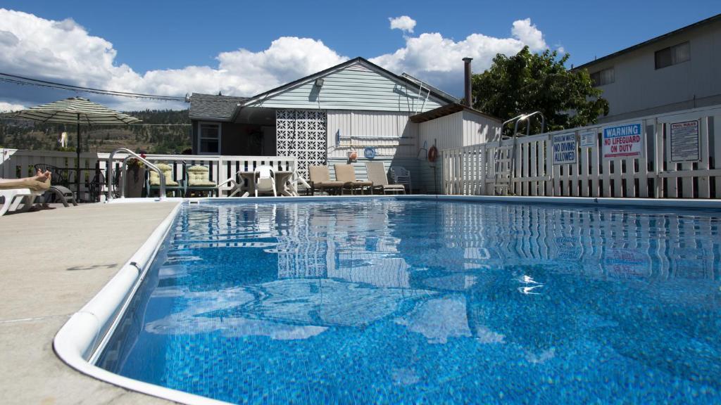 a swimming pool with blue water in front of a house at Valley Star Motel in Penticton
