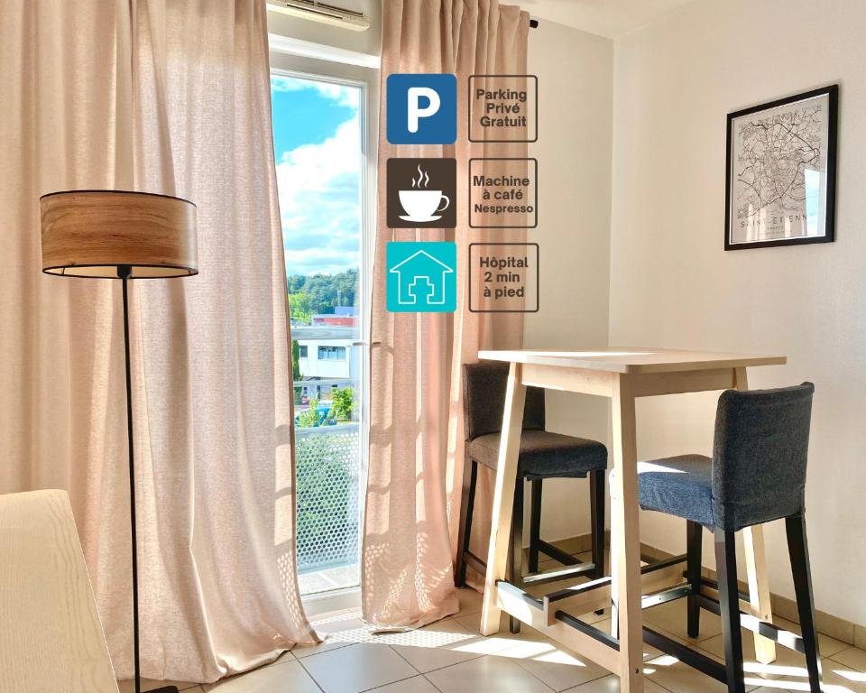 Saint-Priest-en-JarezにあるAppartement en face Hopital Nordのテーブルと椅子2脚、窓が備わる客室です。