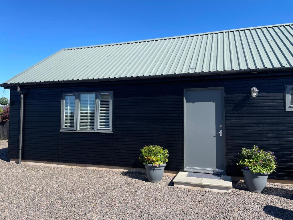 a black house with a white door and two plants at The Chalet in Inverness