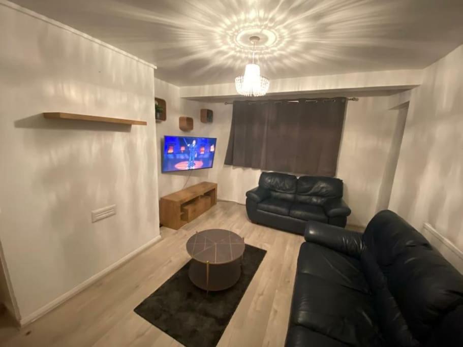 a living room with a black leather couch and a table at 2 bedroom flat with balcony London in London