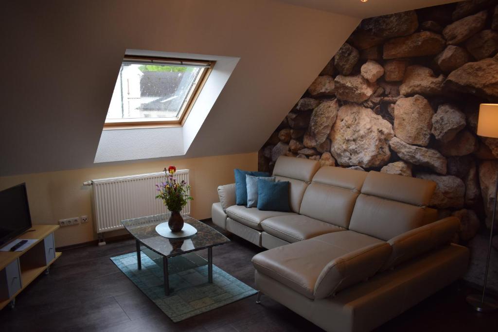 a living room with a couch and a stone wall at Ferienhaus & Weingut am Steingebiss in Billigheim-Ingenheim