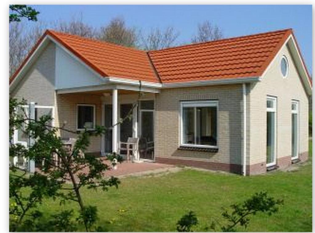 una pequeña casa con techo naranja en Mees, en Hollum