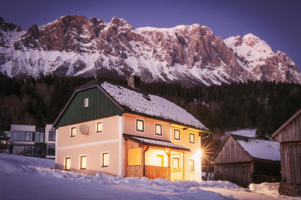 a house in the snow in front of a mountain at Ferienhaus Schwöllerbauer in Sankt Martin am Grimming