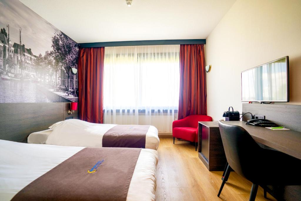 a hotel room with two beds and a television at Bastion Hotel Groningen in Groningen