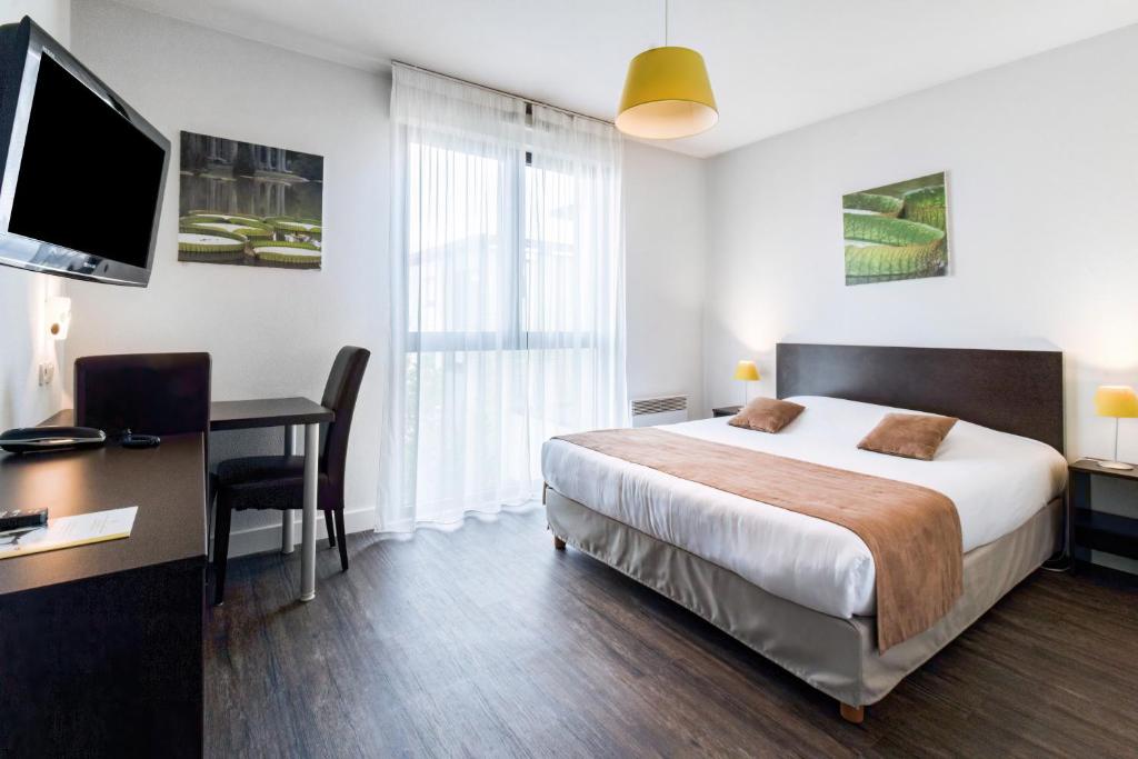 a hotel room with a bed and a desk with a computer at All Suites Pau – Zénith in Pau