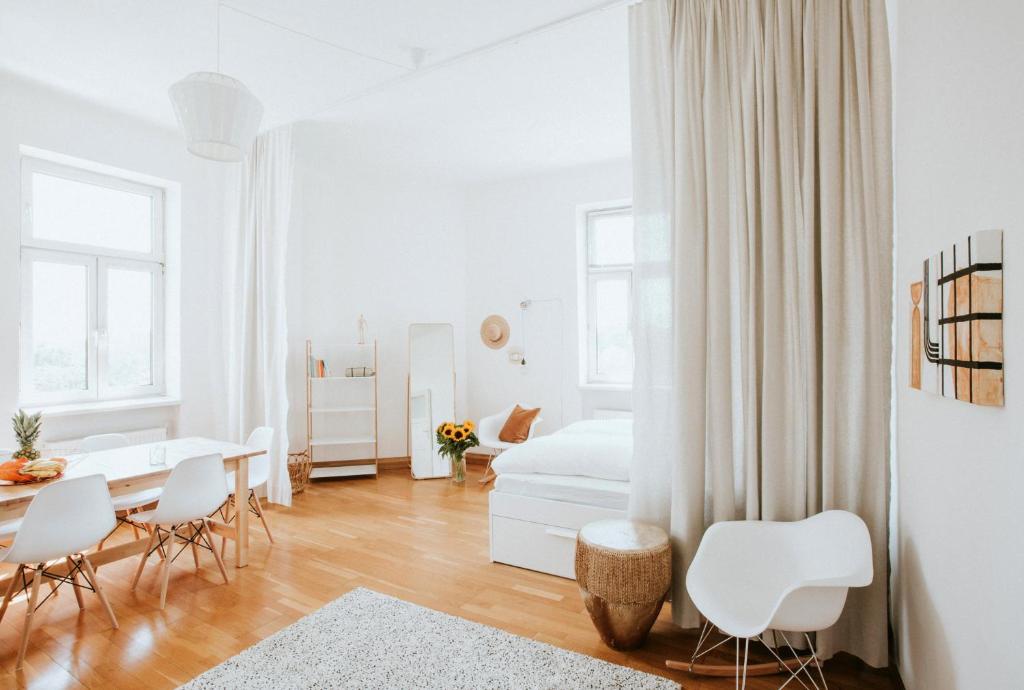 ウィーンにあるCentral Design-Apartment next to Belvedere Castleのダイニングルームとベッドルームが備わる白いアパートメントです。