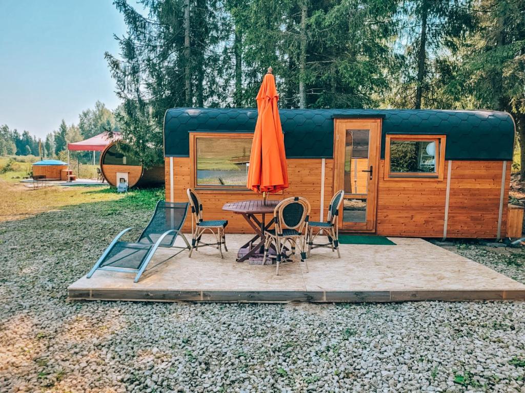 uma tenda com uma mesa, um guarda-sol e cadeiras em Brīvdienu namiņi Kalnozoli em Indrāni