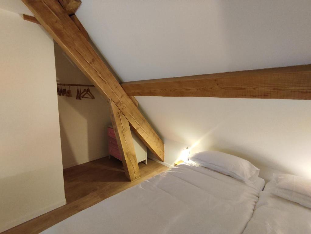 a white bed in a room with wooden beams at ImaginaSoi in Dunières