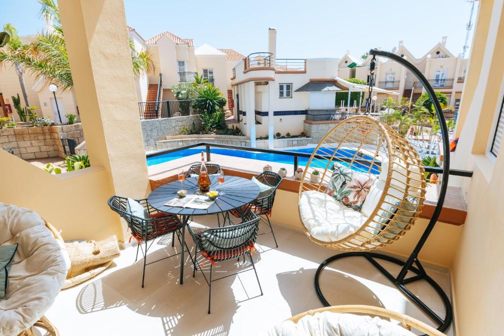 a balcony with a table and chairs and a pool at Amazing renovated pool view Apt, Aircon, 2 min to Fañabe Beach in Adeje
