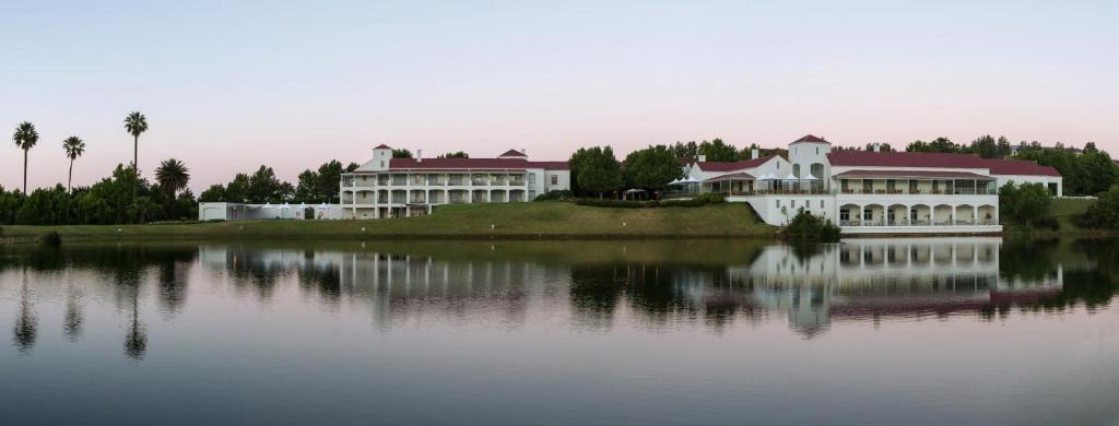 a large white building on the edge of a lake at Asara Wine Estate & Hotel in Stellenbosch