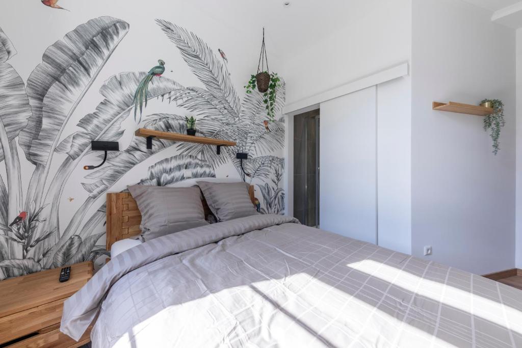 una camera da letto con un grande letto e carta da parati tropicale di IQS Rooms - Chambre double avec salle de bain a Lussemburgo
