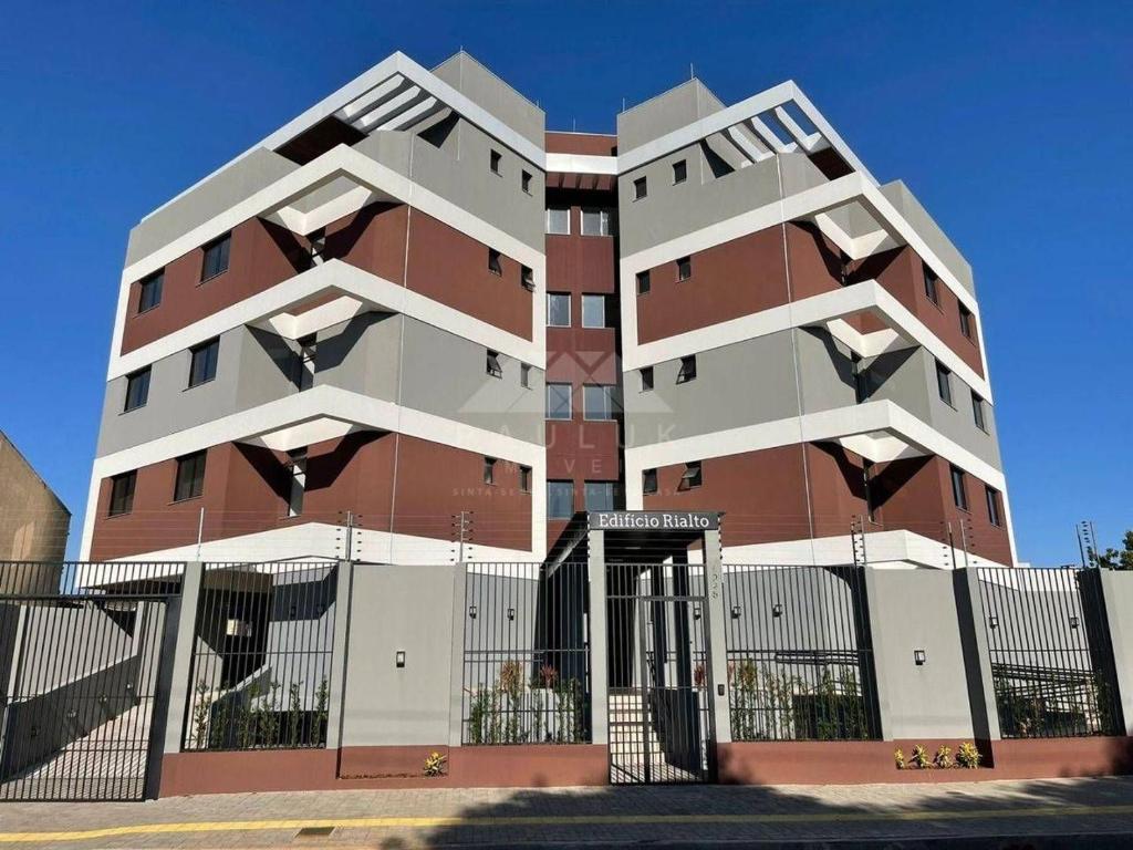 a tall building with a fence in front of it at NOVOS apartamentos STUDIO do ladinho do Paraguai in Foz do Iguaçu