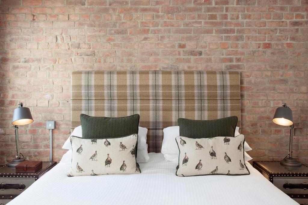 a bed with two pillows and a brick wall at The Gannet Inn in St Ives