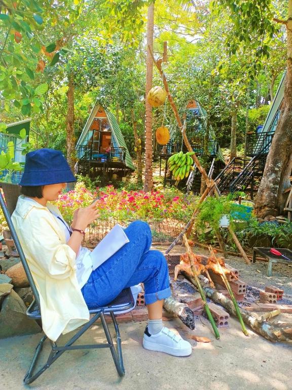 a woman sitting in a chair reading a book at Homestay De la Rosa - Côn Đảo in Con Dao