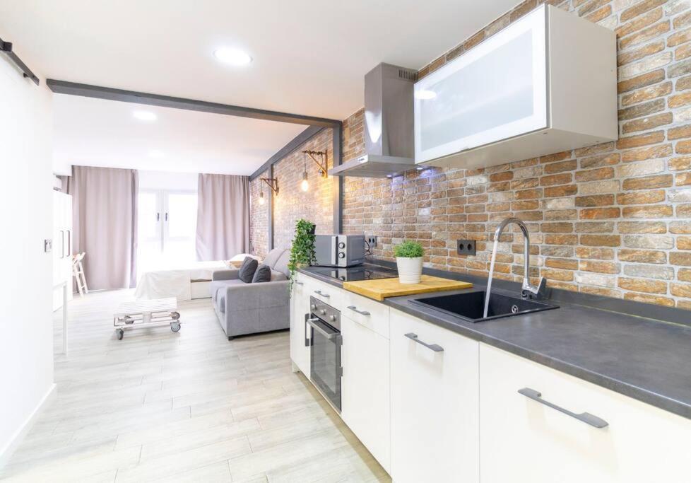 a kitchen with white cabinets and a brick wall at Acogedor Loft Bazán - Alicante Centro in Alicante