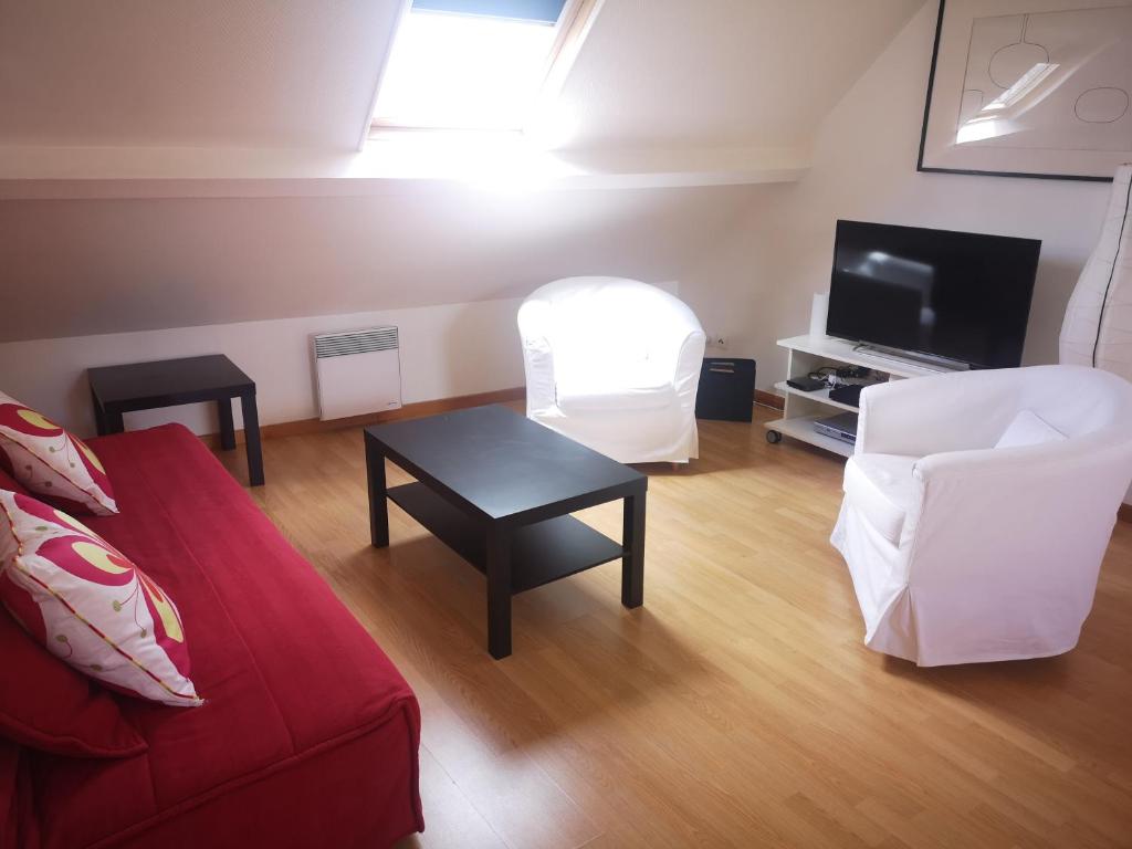 a living room with a red couch and a tv at Appartement Chaleureux in Albert