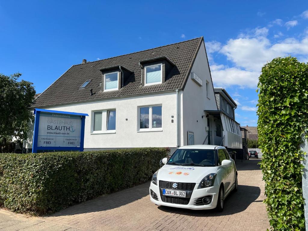 een witte auto geparkeerd voor een huis bij Gästehaus Blauth in Cuxhaven
