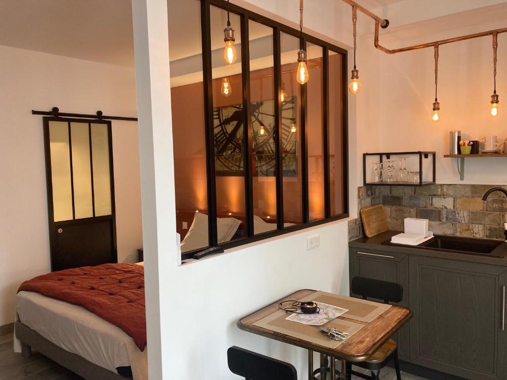Zimmer mit einem Bett und einem Tisch sowie einer Küche in der Unterkunft Les lofts in LʼIsle-sur-la-Sorgue