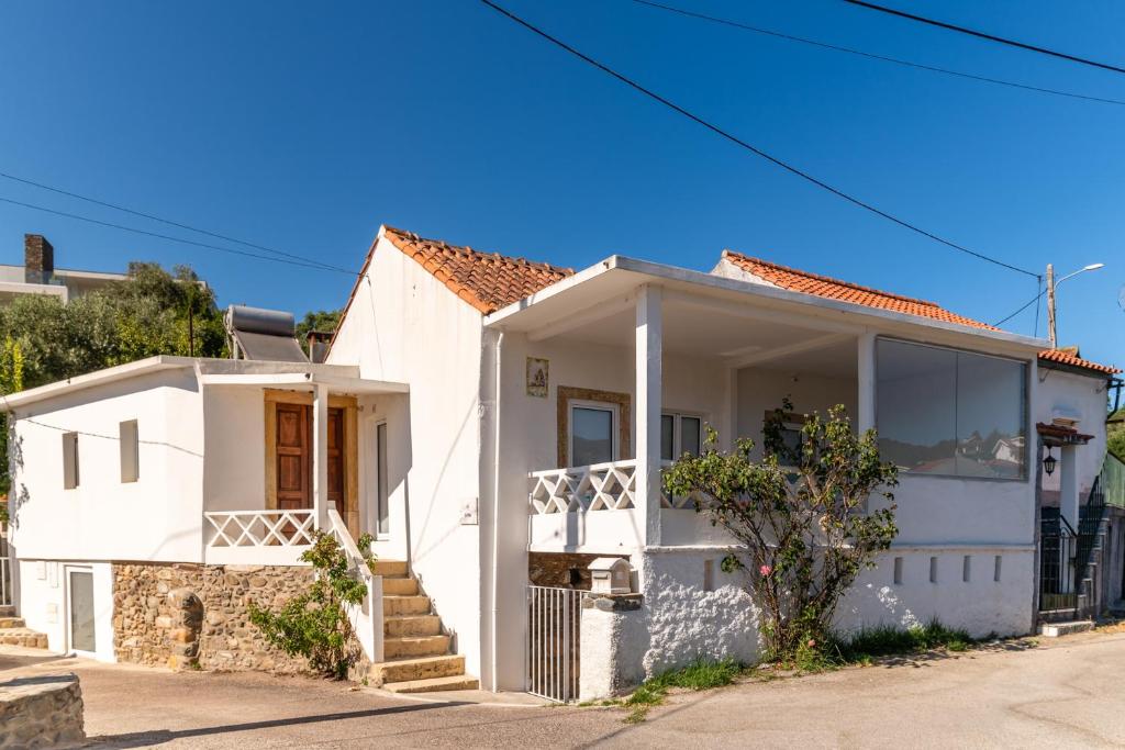 a white house on a street at Casa das Rosas - Roses House in Miranda do Corvo