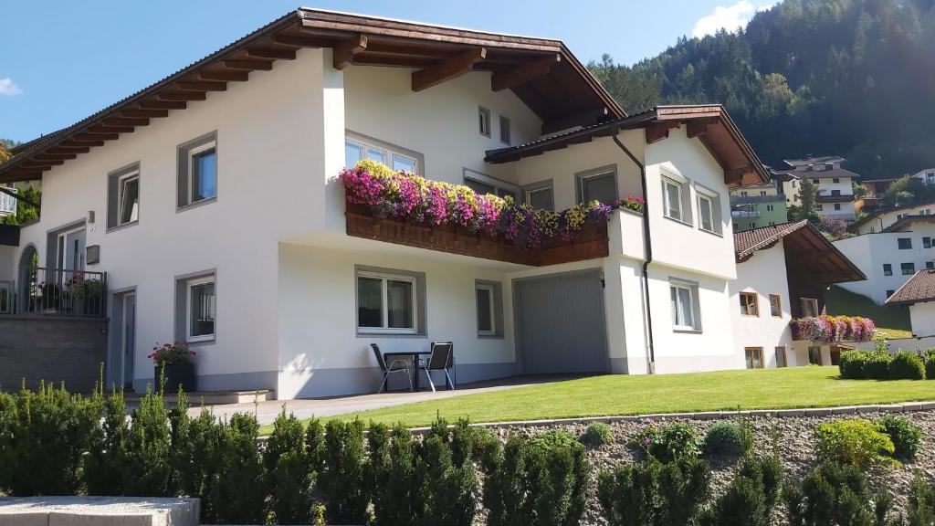 a white house with a balcony with flowers at Ferienwohnung Tanja inklusive Sommercard in Jerzens