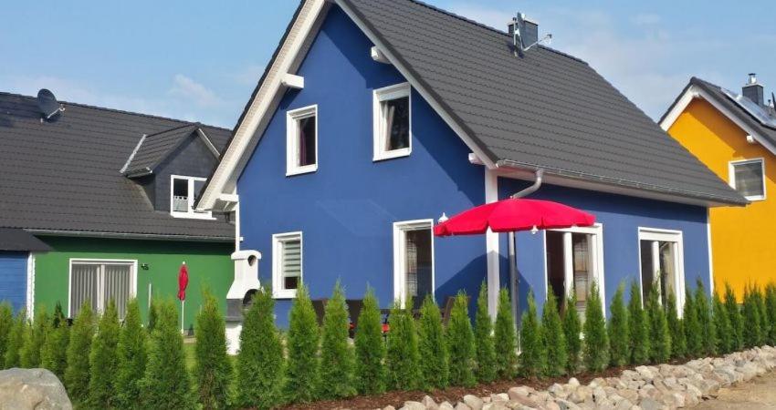 una casa azul con un paraguas rojo delante de ella en Ferienhaus Strandräuber en Marienfelde